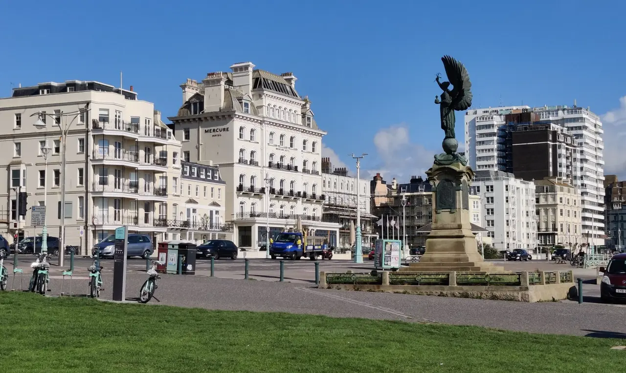 The Peace Statue on the seafront lawns at the Brighton and Hove border, with white seafront hotels behind under a blue sky