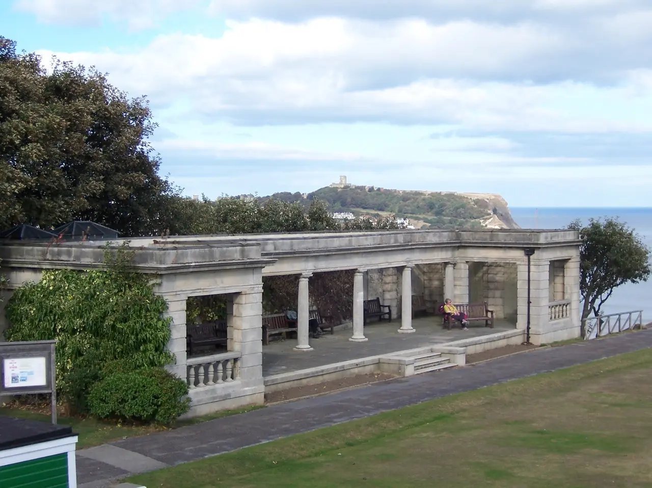 The stone shelter in South Cliff Gardens on the Esplanade, with the castle headland across the South Bay behind