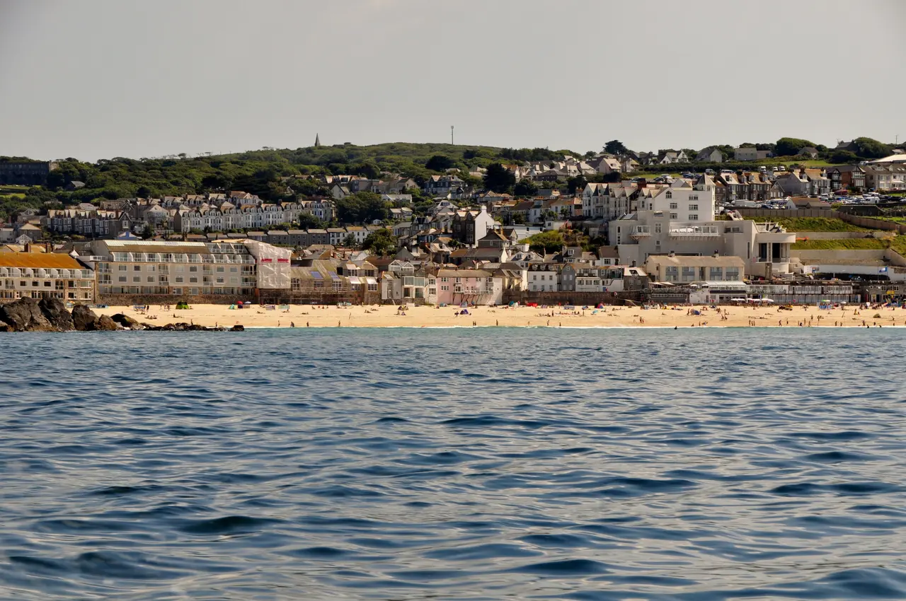 St Ives seen from the sea, with the long sand of Porthmeor Beach below the white Tate building and houses on the hill behind