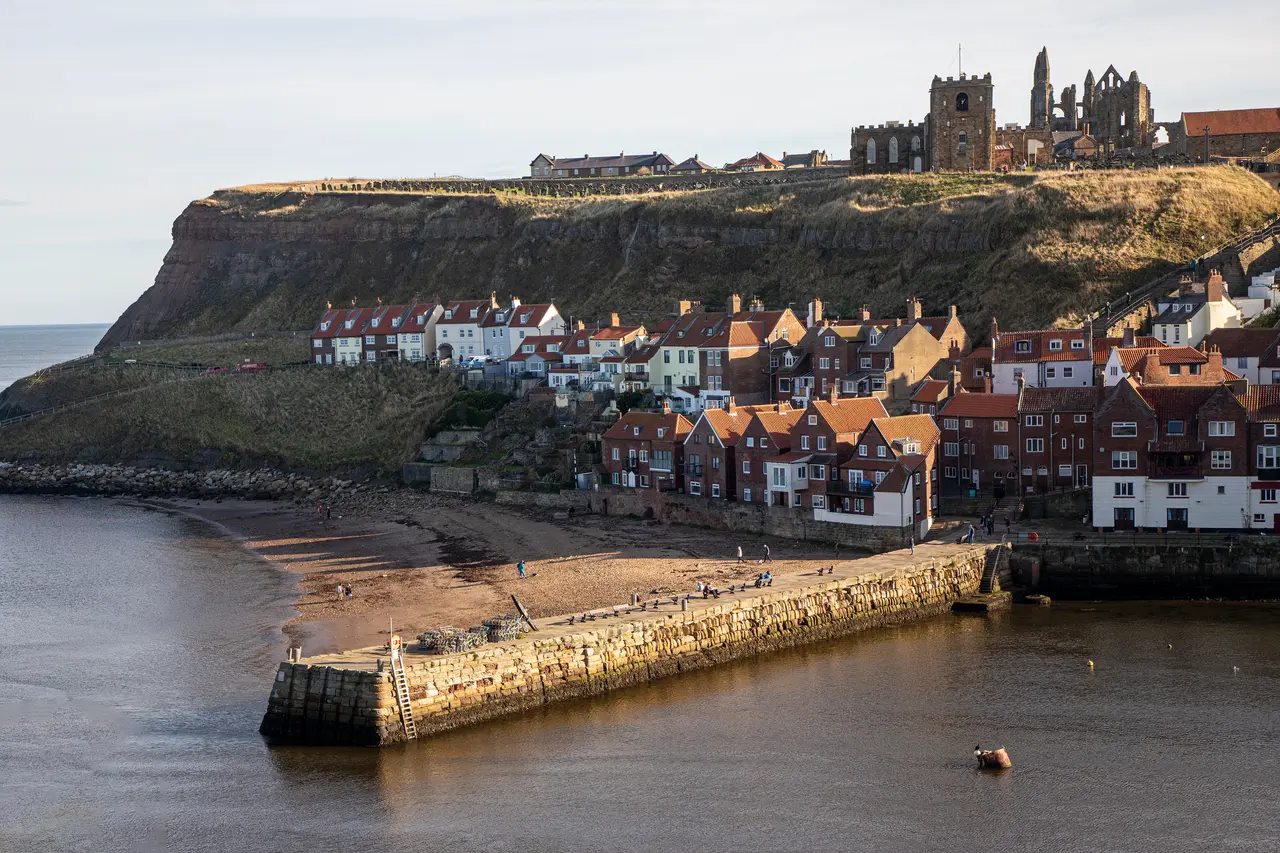 Tate Hill Pier and the small sandy beach beside it, below the cottages of the East Side and the abbey ruins on the cliff