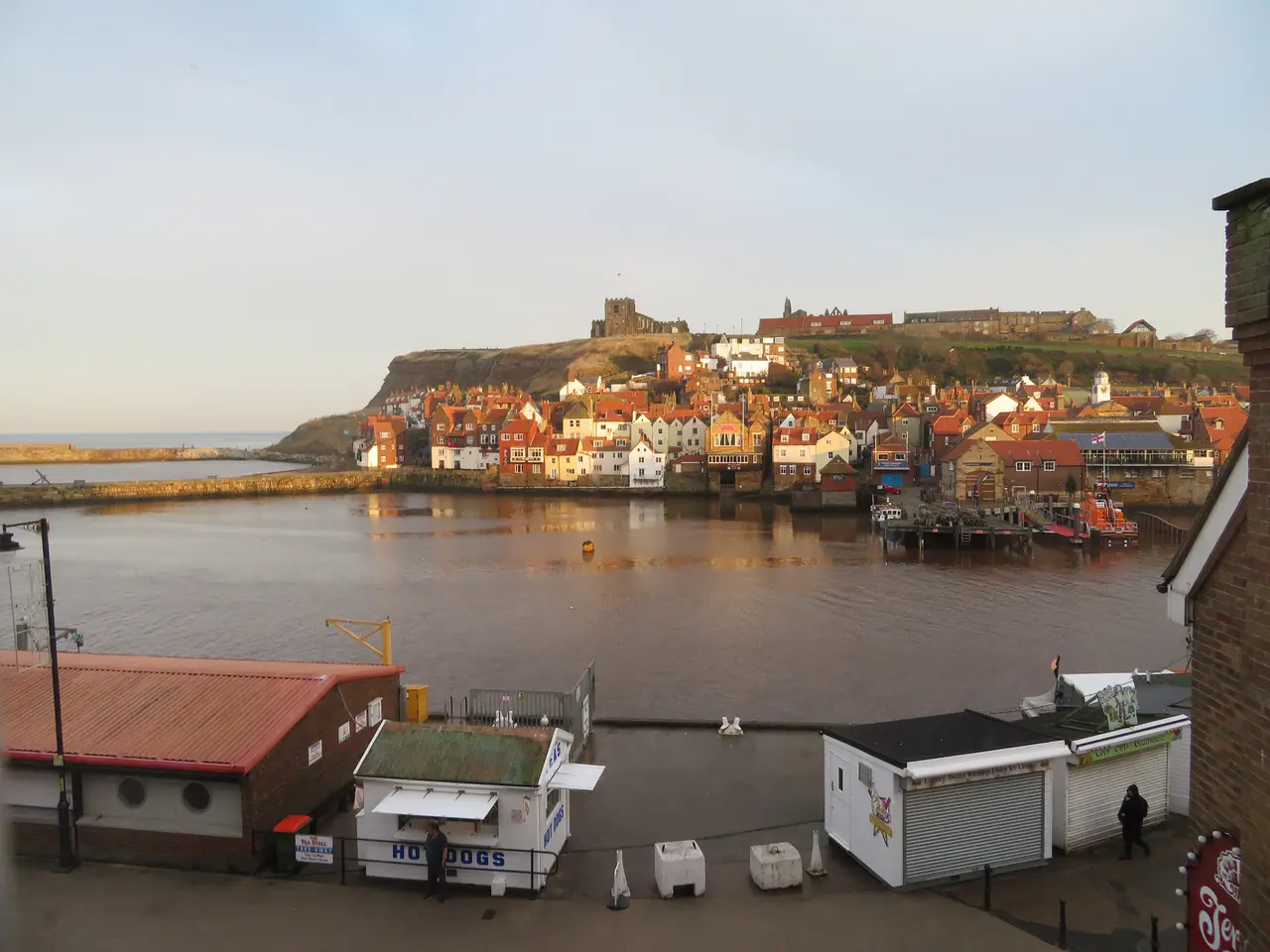 The East Side of Whitby across the harbour: rows of red-roofed cottages below the clifftop church and abbey ruins