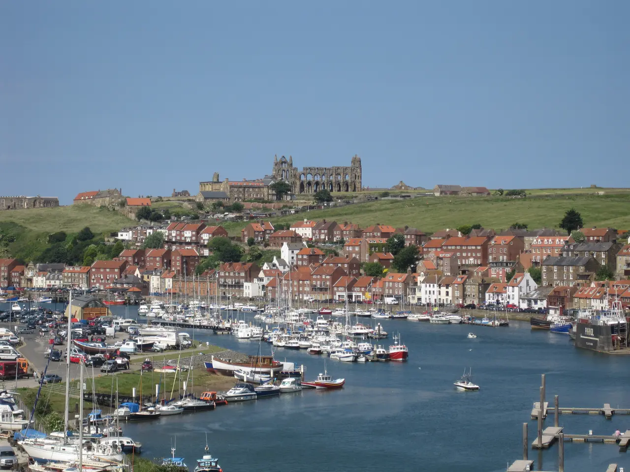 Whitby's harbour full of moored boats below the East Cliff, with the ruined abbey and St Mary's Church on the skyline