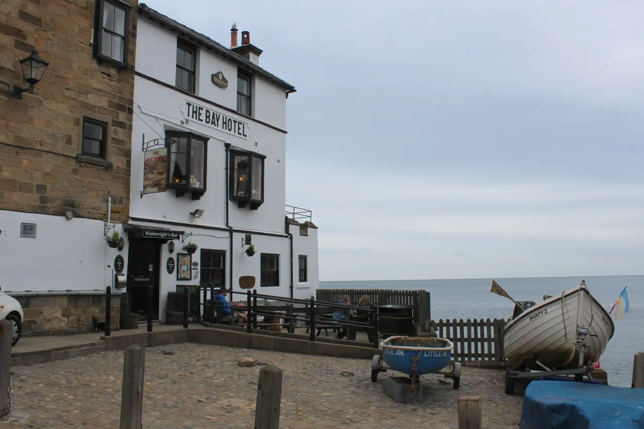 The white-fronted Bay Hotel at the bottom of Robin Hood's Bay, by the slipway with a small boat in front and the sea beyond