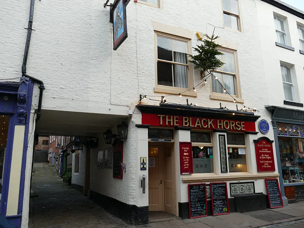 The Black Horse on Church Street, a narrow white-painted pub with its name on a red sign over the door