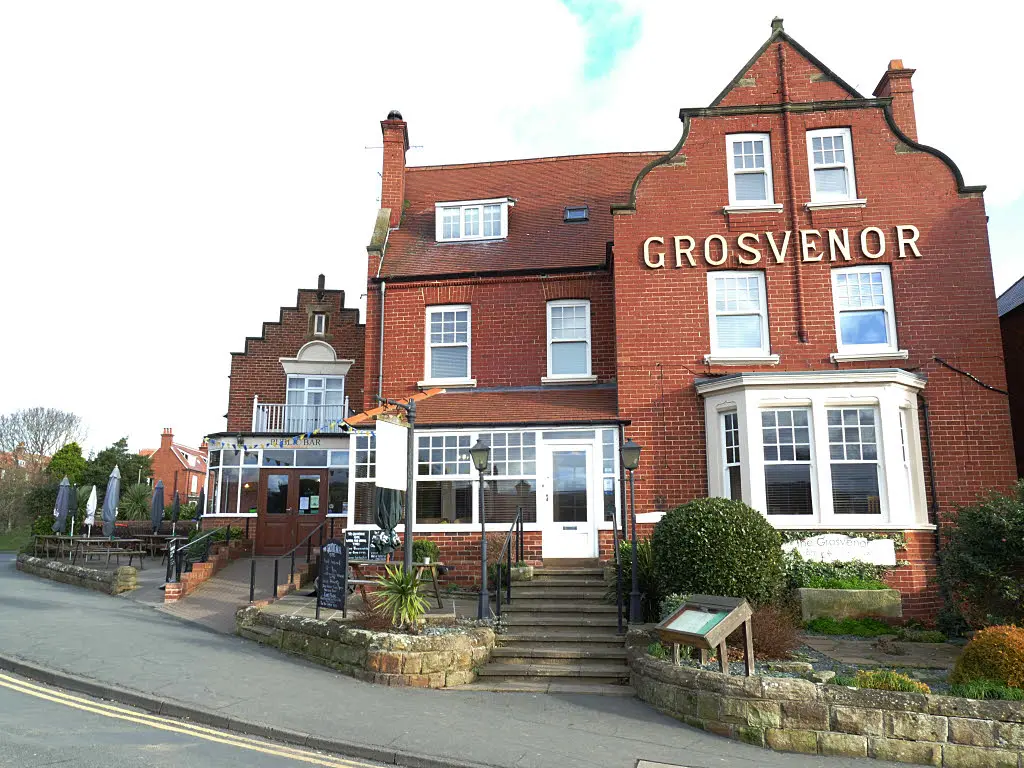 The Grosvenor in Robin Hood's Bay, a red-brick hotel with its name in white letters on the gable and steps up to the door
